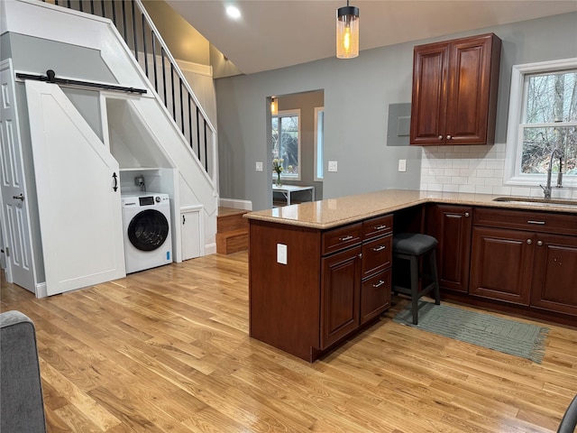 kitchen with pendant lighting, washer / dryer, tasteful backsplash, sink, and kitchen peninsula