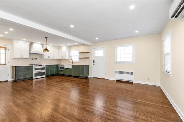 kitchen with premium range hood, green cabinets, radiator heating unit, a wall mounted air conditioner, and range with two ovens