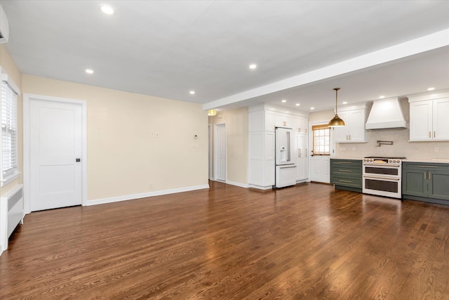 kitchen with dark hardwood / wood-style flooring, premium appliances, hanging light fixtures, and wall chimney exhaust hood