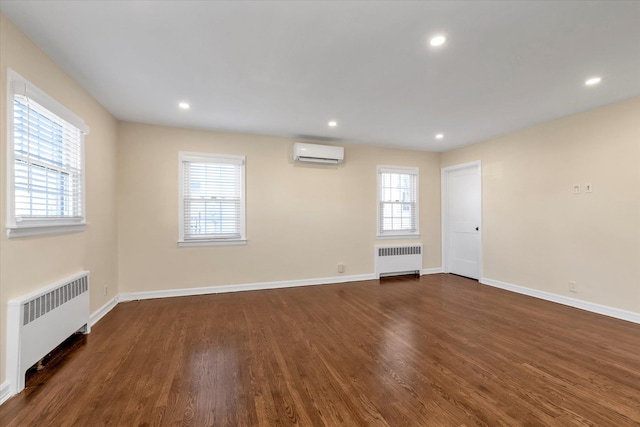 spare room featuring a wall mounted air conditioner, dark hardwood / wood-style flooring, and radiator