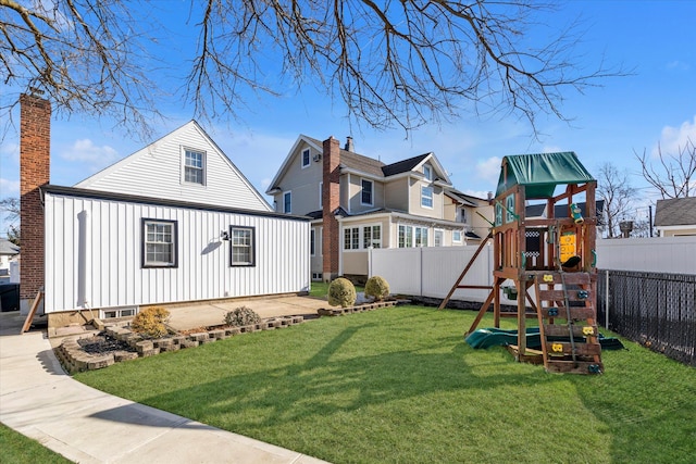 rear view of house featuring a lawn and a playground