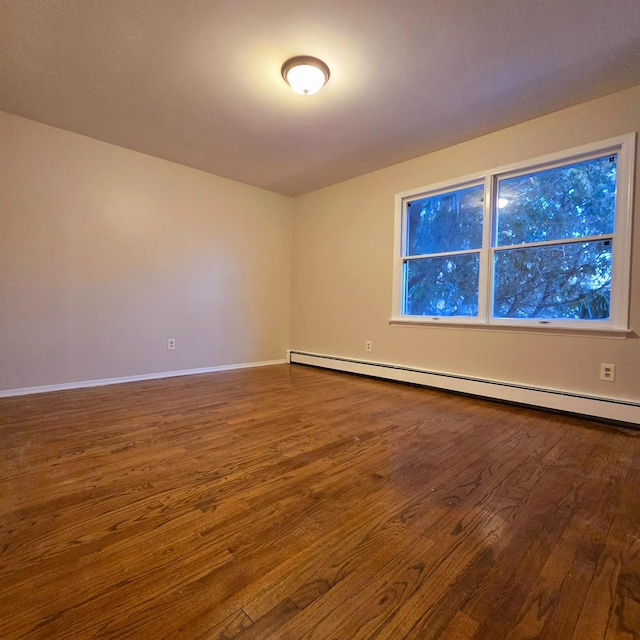 empty room featuring baseboard heating and hardwood / wood-style floors