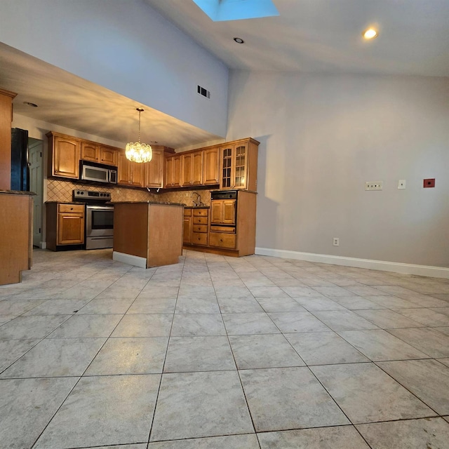 kitchen with a kitchen island, decorative backsplash, hanging light fixtures, a skylight, and appliances with stainless steel finishes