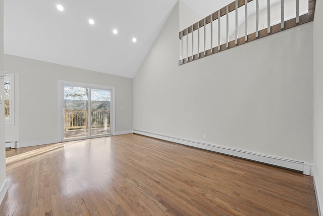 unfurnished living room with high vaulted ceiling, hardwood / wood-style floors, and a baseboard heating unit