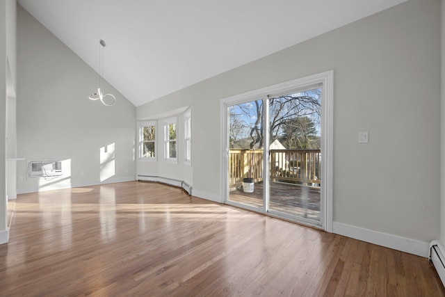 unfurnished living room with a baseboard radiator, hardwood / wood-style flooring, a wall mounted AC, and vaulted ceiling