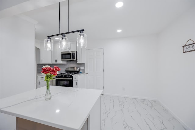 kitchen featuring decorative backsplash, decorative light fixtures, gas range oven, white cabinets, and a center island