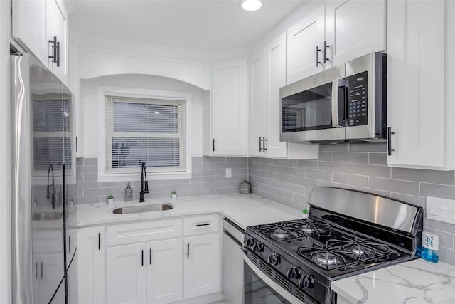 kitchen with light stone counters, sink, white cabinetry, and appliances with stainless steel finishes