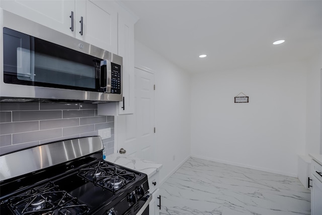 kitchen with light stone countertops, white cabinets, decorative backsplash, and appliances with stainless steel finishes