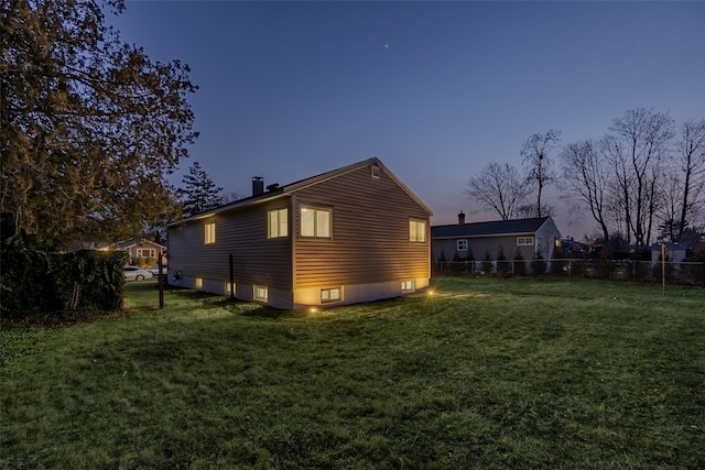 property exterior at dusk featuring a lawn