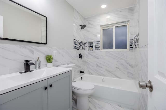 full bathroom with tile walls, tiled shower / bath combo, vanity, and toilet