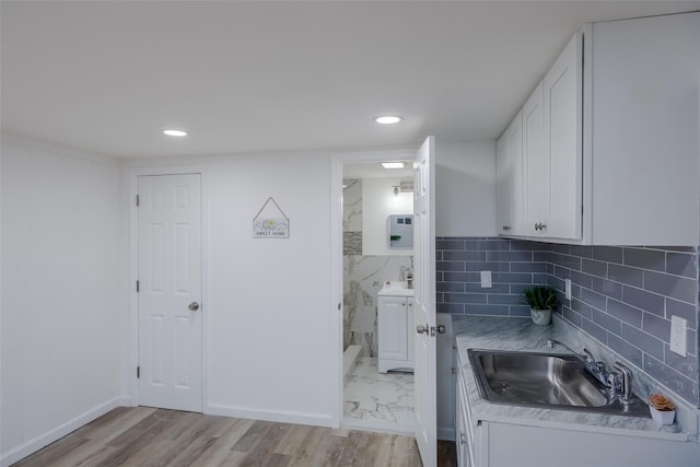 kitchen featuring sink, white cabinetry, backsplash, and light wood-type flooring