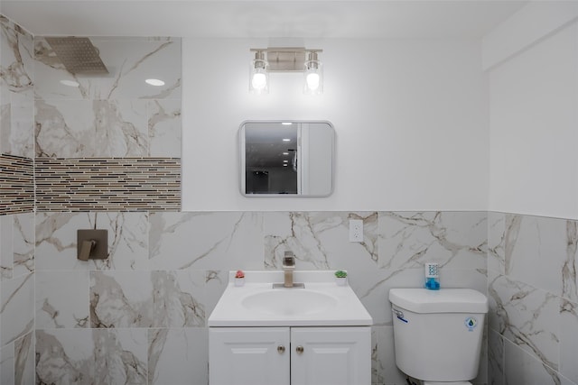 bathroom with toilet, tile walls, and vanity