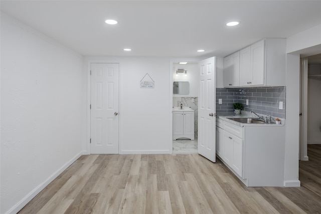 kitchen featuring tasteful backsplash, sink, white cabinetry, and light hardwood / wood-style floors