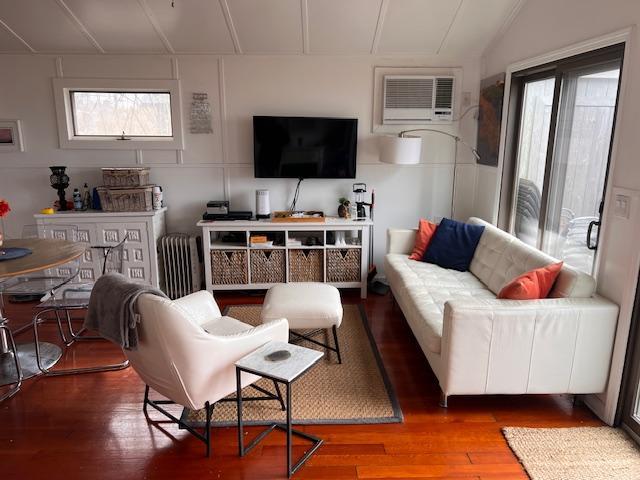 living room featuring a healthy amount of sunlight, a wall unit AC, and hardwood / wood-style floors