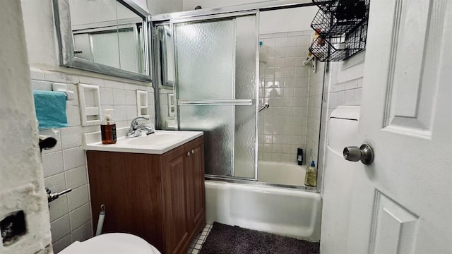 full bathroom with toilet, vanity, backsplash, tile walls, and bath / shower combo with glass door