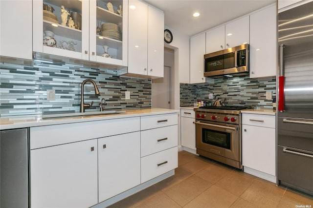 kitchen featuring tasteful backsplash, white cabinets, premium appliances, and sink