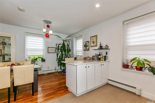 kitchen featuring decorative light fixtures, white cabinets, baseboard heating, and kitchen peninsula