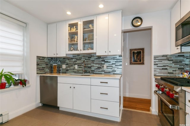 kitchen with sink, white cabinetry, light tile patterned floors, and stainless steel appliances