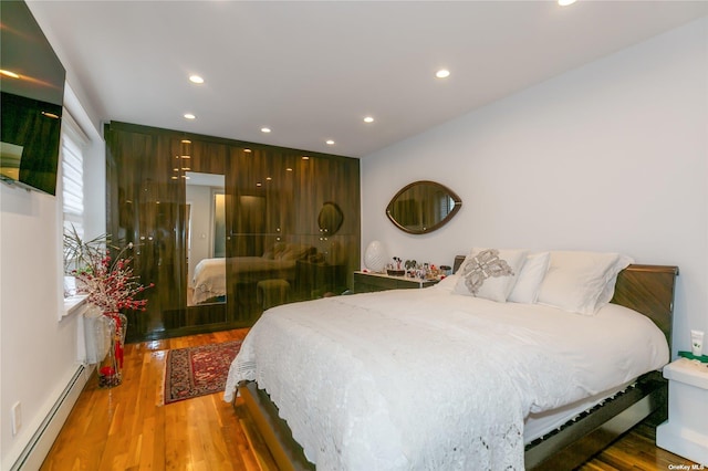 bedroom with a baseboard heating unit and hardwood / wood-style floors