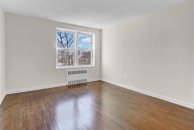 spare room with dark wood-type flooring and radiator heating unit