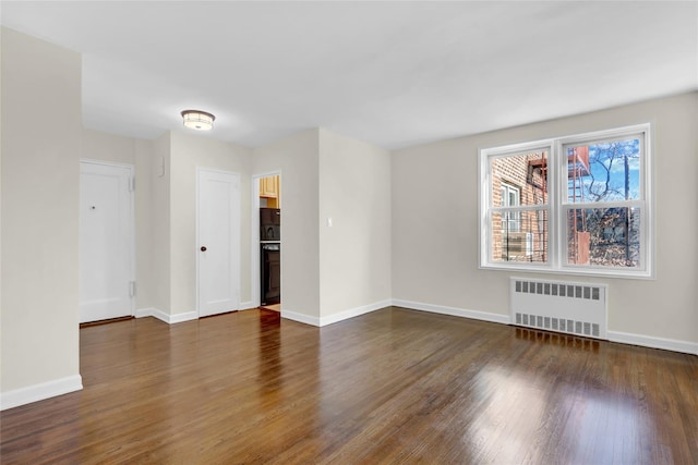 spare room featuring radiator and dark wood-type flooring