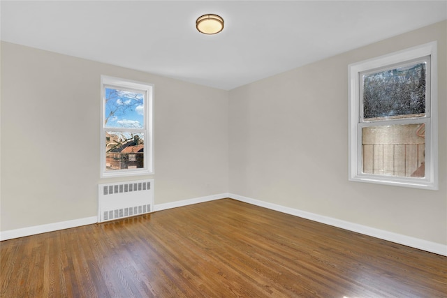 unfurnished room featuring hardwood / wood-style floors and radiator heating unit