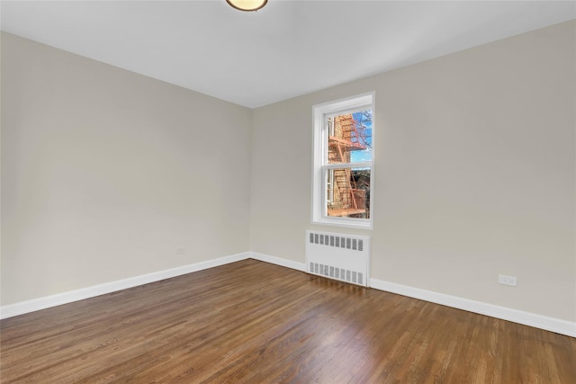 spare room with dark hardwood / wood-style flooring and radiator heating unit