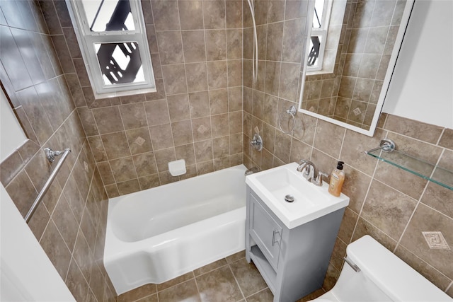 full bathroom featuring tile walls, toilet, vanity, and tiled shower / bath combo