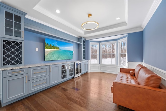 living room with ornamental molding, dark hardwood / wood-style flooring, and a raised ceiling