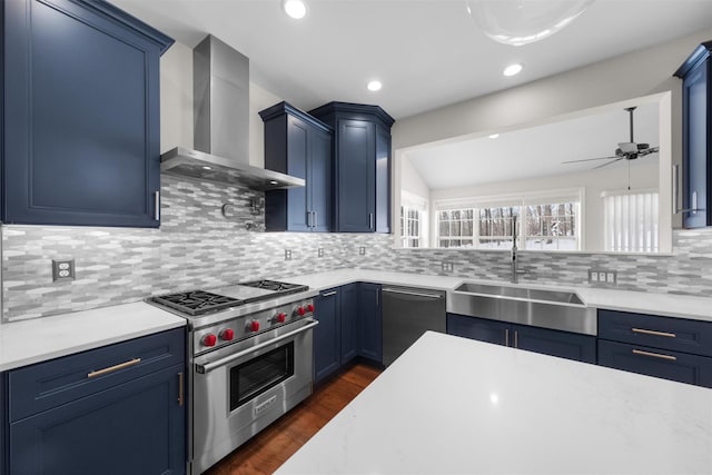 kitchen with stainless steel appliances, sink, blue cabinets, and wall chimney range hood