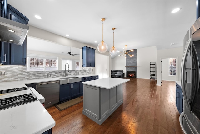 kitchen with sink, blue cabinets, stainless steel appliances, and a kitchen island