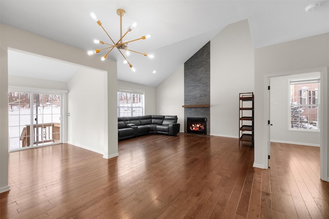 unfurnished living room with an inviting chandelier, dark hardwood / wood-style flooring, lofted ceiling, and a fireplace