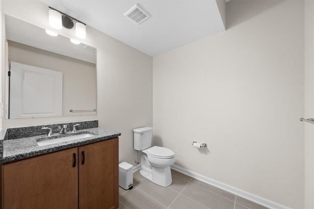 bathroom with toilet, vanity, and tile patterned flooring