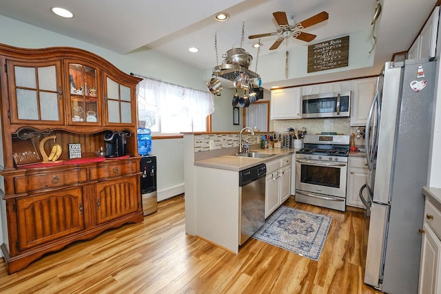 kitchen featuring white cabinetry, sink, decorative backsplash, light hardwood / wood-style floors, and stainless steel appliances