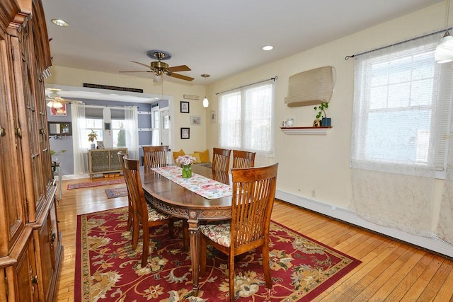 dining area with a baseboard radiator, light hardwood / wood-style floors, and ceiling fan