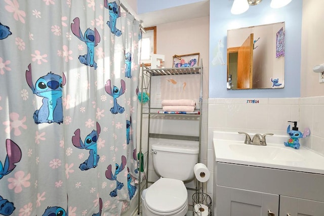 bathroom featuring vanity, toilet, curtained shower, and tile walls