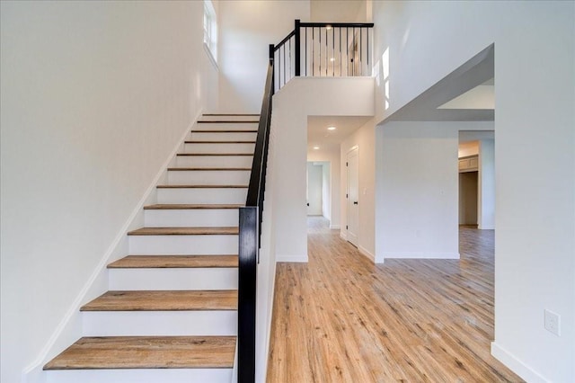 stairs with hardwood / wood-style floors and a high ceiling