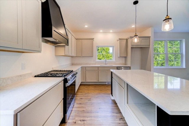 kitchen featuring pendant lighting, appliances with stainless steel finishes, premium range hood, sink, and light stone counters