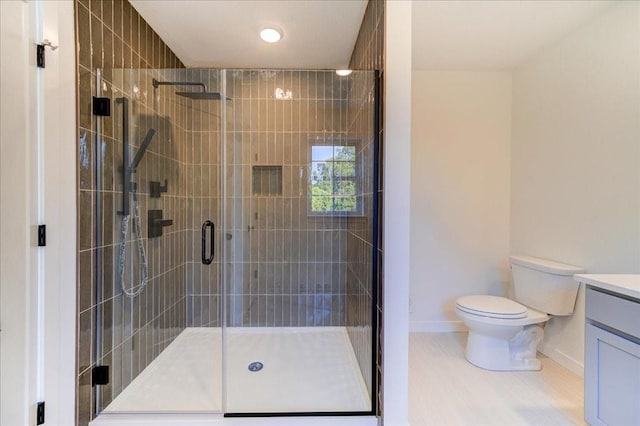 bathroom with toilet, vanity, wood-type flooring, and a shower with door