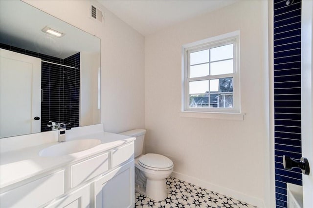 bathroom featuring tiled shower, vanity, and toilet