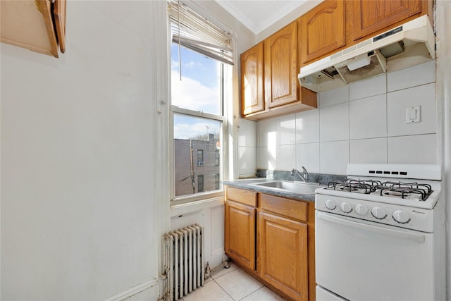 kitchen with light tile patterned floors, radiator heating unit, decorative backsplash, white gas range, and sink