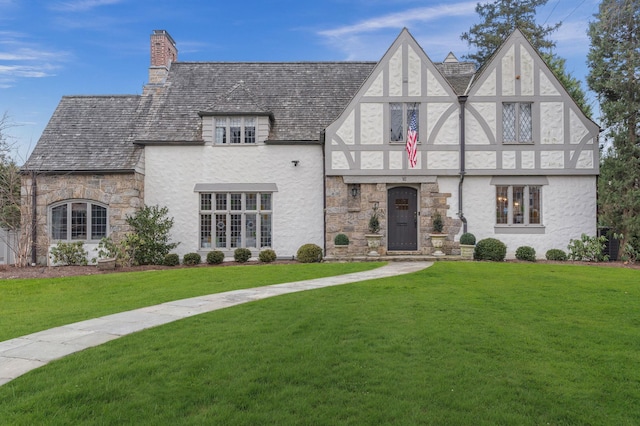 tudor-style house featuring a front lawn and central air condition unit