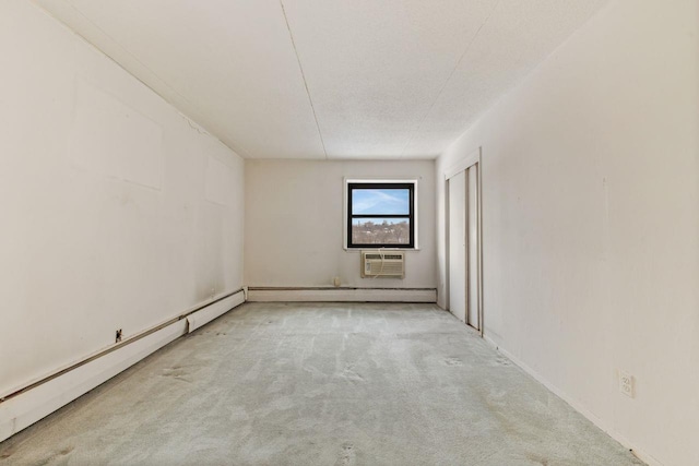 empty room with light colored carpet, a wall mounted AC, a textured ceiling, and a baseboard heating unit