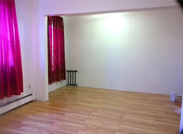 spare room featuring light wood-type flooring and a baseboard heating unit