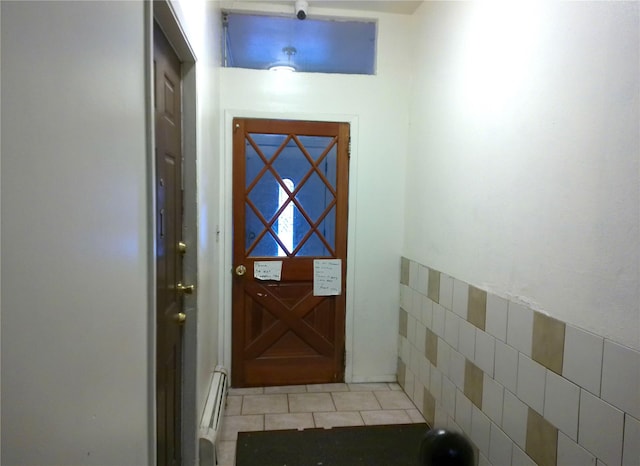 doorway to outside with baseboard heating and light tile patterned flooring