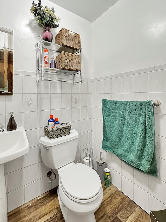 bathroom with toilet, tile walls, and hardwood / wood-style floors