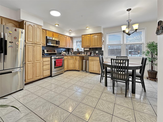 kitchen with backsplash, a notable chandelier, hanging light fixtures, stainless steel appliances, and light tile patterned floors