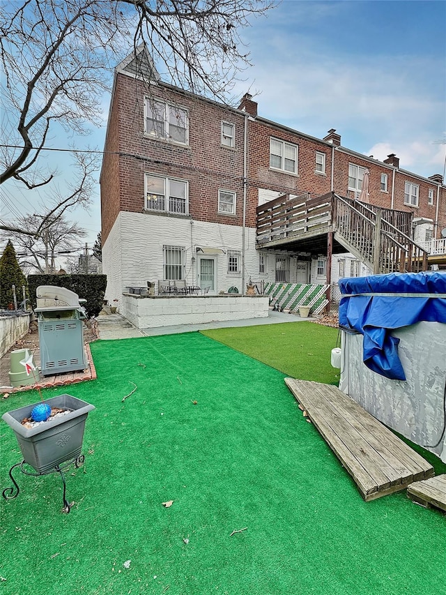 rear view of property featuring a swimming pool side deck and a lawn