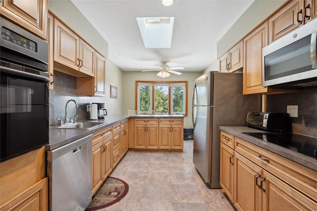 kitchen featuring a skylight, sink, decorative backsplash, ceiling fan, and black appliances