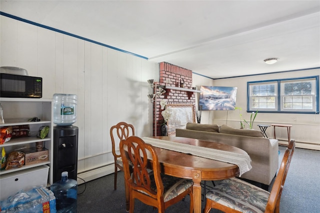 carpeted dining room featuring wooden walls, a brick fireplace, and a baseboard heating unit